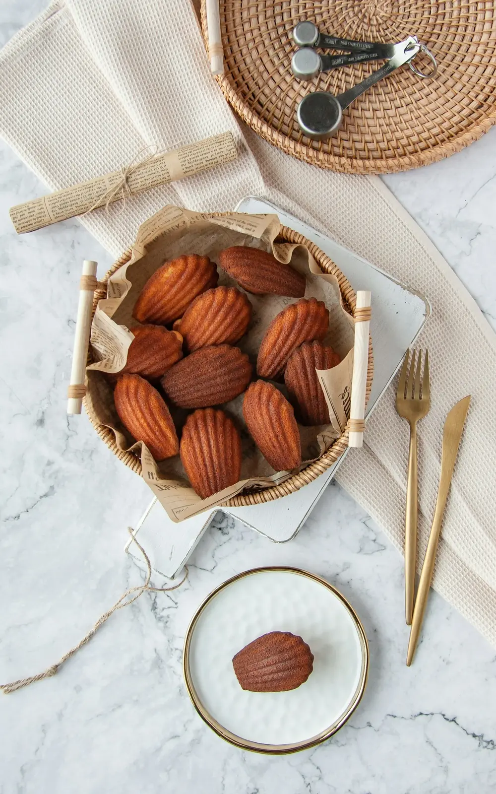 Madeleines in a parchment-lined rattan basket on white marble